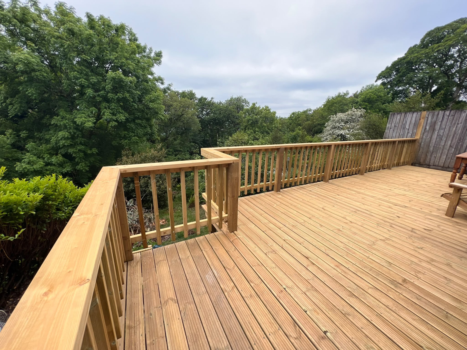 Raised timber deck with matching balustrade overlooking trees, built by PC Landscaping in South Devon