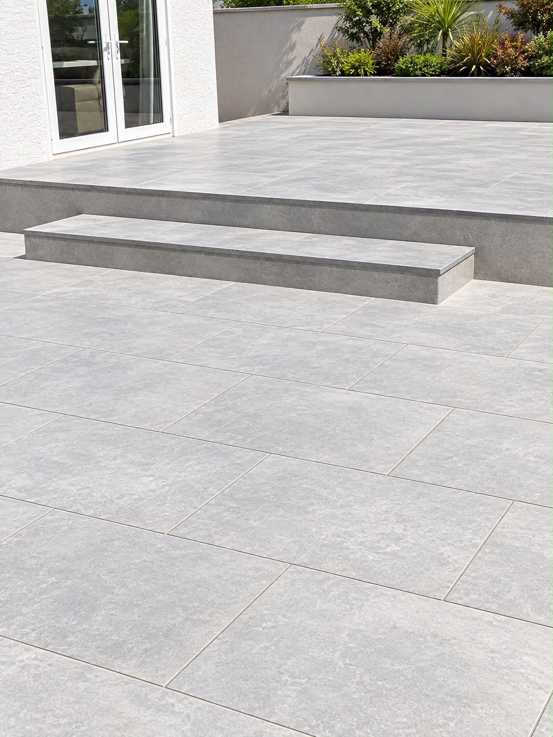 Grey porcelain patio laid by PC Landscaping at a South Devon home, with tight joints and a level finish